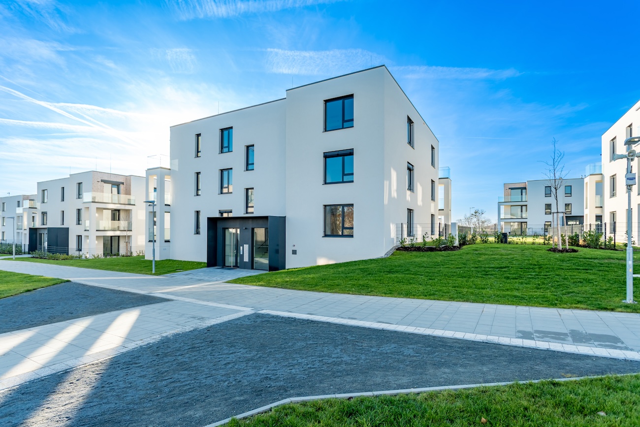 Modern residential complex with green areas and pathways on sunny day